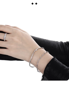 Silver jewelry set detail featuring an irregular textured cuff and a pavé stone ring