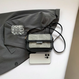 Minimalist black and grey-green textured rectangular crossbody bag on a dark blazer