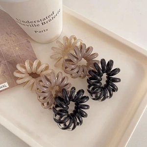 Detail of six colorful spiral hair ties in jelly colors arranged on a white tray