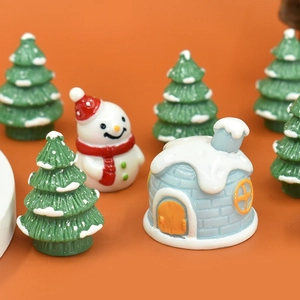 Macro shot of miniature resin snowman, igloo, and green Christmas trees on orange backdrop
