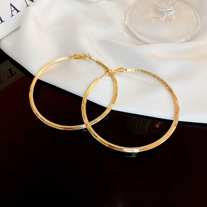 Detailed view of large gold-plated hoop earrings with frosted texture and polished finish
