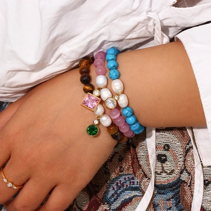 Detail of stacked beaded bracelets with zircon pendants and gold ring on model hand