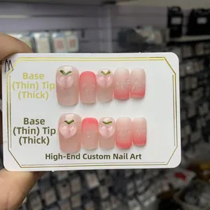Détail de faux ongles faits main dégradé rose avec motifs de pêche et gouttes d'eau 3D