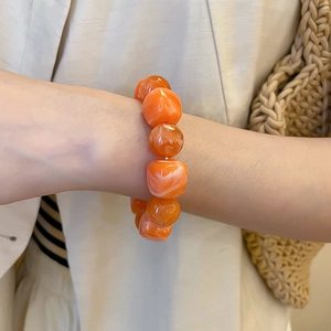 Détail de grosses perles en acrylique orange avec texture marbrée sur un bracelet d'été