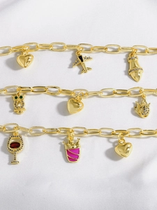 Dettaglio di bracciali a catena placcati oro 18 carati con ciondoli a cuore e aereo su seta
