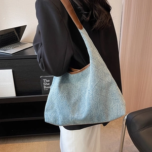 Blue denim tote bag with brown leather straps and quilted pattern shown on model