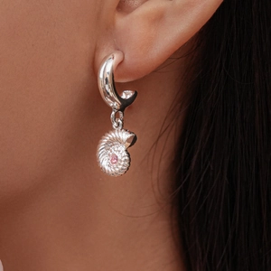 Macro shot of a silver shell hoop earring with a pink zircon stone inlay on model