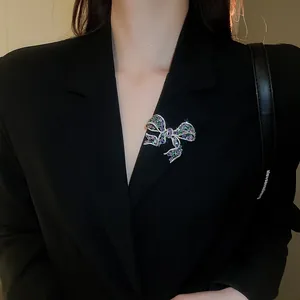 Detailed view of luxury bow brooch with purple and green zircon crystals on a black suit