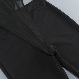 Detail shot of black jumpsuit featuring sheer mesh paneling and high-quality stitching