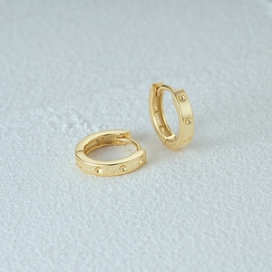 Detailed macro view of gold-plated 925 silver hoop earrings with textured surface
