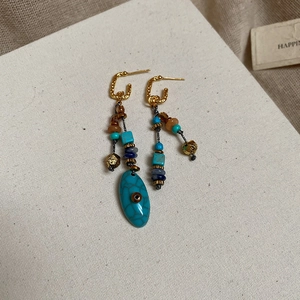 Dettaglio di orecchini vintage con perle turchesi e nappe colorate in stile retrò