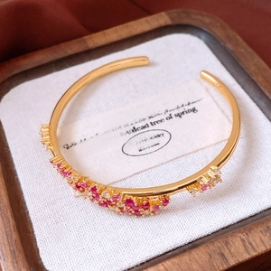 Détail du bracelet ondulé plaqué or 18 carats avec zircons dans un écrin en bois élégant