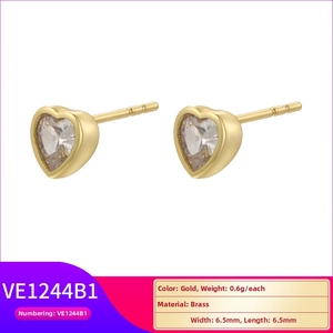 Detailed macro view of heart-shaped gold-plated brass stud earrings with clear zircon stones