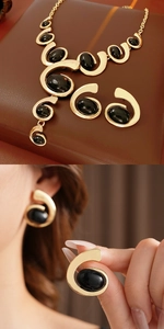Vintage gold metal and black oval stone jewelry set featuring necklace and earrings