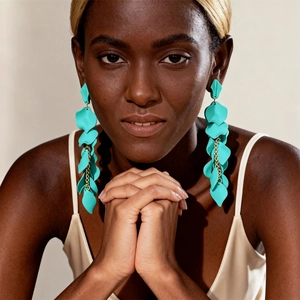 Detail of turquoise petal drop earrings with gold chains on model for vacation look