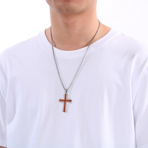 Gros plan d'un pendentif croix en acier argenté avec incrustation bois sur un mannequin