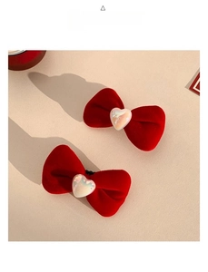 Close-up of red velvet bow hair clips with heart-shaped iridescent center accents