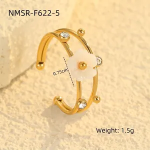 Detail of 18K gold flower ring with white shell petal and crystal accents on stone