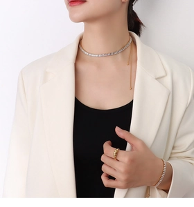 Dettaglio della modella che indossa una collana a catena bicolore e set di gioielli coordinati
