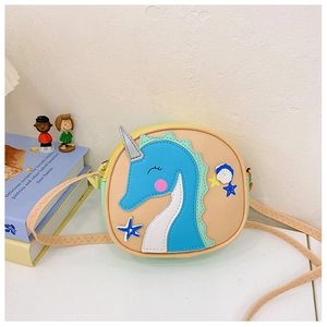 Détail du sac bandoulière rond beige avec écussons hippocampe bleu et étoile de mer