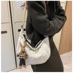 Detailed side view of white quilted half-moon crossbody bag with cute rabbit charm