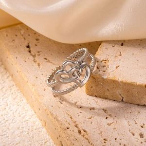 Detailed macro of silver stainless steel intertwined hearts ring on stone and silk