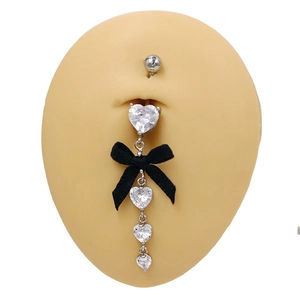 Détail d'un piercing de nombril en argent avec zircon coeur blanc et noeud noir sur peau