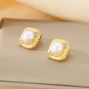 Detailed shot of golden square pearl earrings with small rhinestones on textured metal