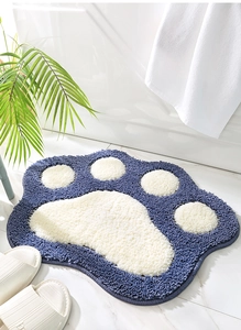 Close-up of a blue and white cat paw bath mat with soft plush texture in a cozy bathroom