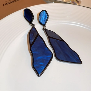 Detail of blue marble resin geometric drop earrings featuring a black border on white plate