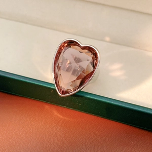 Detail of pink heart-shaped crystal ring with silver setting on a green jewelry box