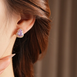Close-up of a purple gourd-shaped crystal earring with small diamonds on model ear