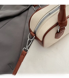 Close-up of contrast stitching on canvas Boston bag with leather trim and silver hardware