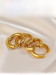 Macro detail of thick 18K gold plated stainless steel hoops on beige silk fabric