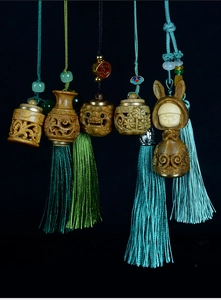 Detailed view of hand-carved sandalwood pendants with silk tassels and jade beads