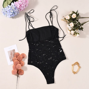 Flat lay of a black lace bodysuit with adjustable tie straps and floral decor