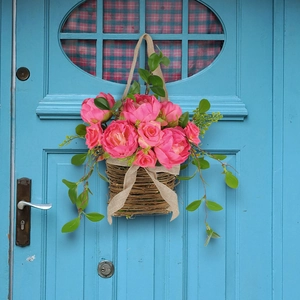 Floral hanging basket with pink roses and green leaves on a vintage blue door