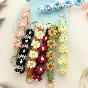 Close-up of handmade macrame daisy flower wristbands with gold metal rings in various colors