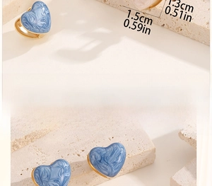 Detail view of blue heart earrings with marble enamel pattern and gold finish