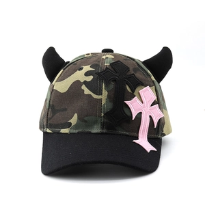 Detail of camo baseball cap with devil horns and pink gothic cross patch embroidery