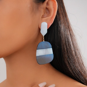Macro shot of geometric blue and white acetate oval earrings worn by a model
