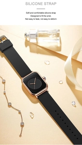 Detail of soft black silicone strap on a square rose gold watch with elegant accessories