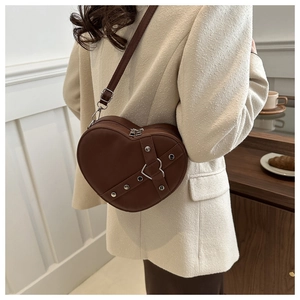 Detailed back view of a brown heart-shaped crossbody bag with silver buckle worn by a model