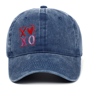 Dettaglio del ricamo XOXO e del cuore sulla texture del cappello in denim lavato.