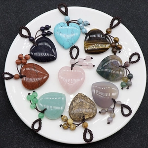 Detailed view of nine colorful heart-shaped gemstone pendants with woven cords on a plate