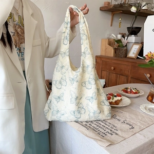 Close-up of cream canvas tote bag with blue butterfly prints and textured fringe fabric