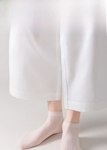 Close-up of pale pink breathable silk socks with vertical ribbed texture on feet