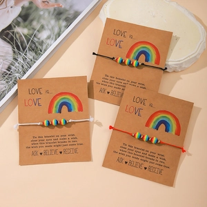 Three handmade woven friendship bracelets with heart beads on a Kraft gift card package