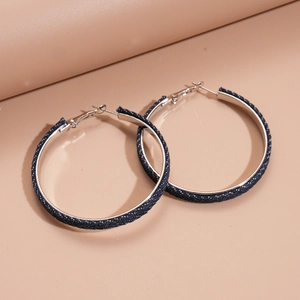 Detail of large circular hoop earrings featuring dark blue denim fabric on silver metal