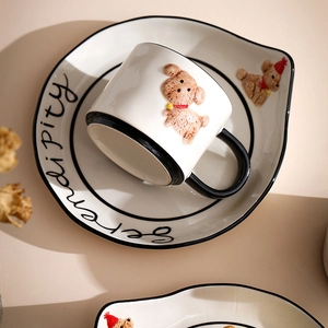 Detailed view of ceramic mug set with 3D teddy bear figure and serendipity text